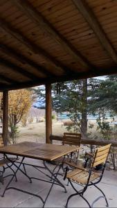 une table de pique-nique en bois et deux chaises sous un toit dans l'établissement Casa Rural entre Bodegas y Viñedos ' El Jarillal", à La Consulta