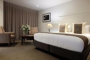 a hotel room with a large bed and a chair at West Meadows of Wanaka in Wanaka