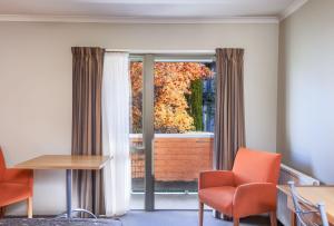 a room with a window with orange chairs and a table at Queenstown Motel Apartments in Queenstown