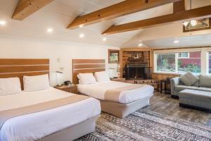 two beds in a hotel room with a fireplace at Andril Fireplace Cottages in Pacific Grove