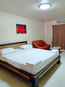 ein Schlafzimmer mit einem großen Bett und einem roten Stuhl in der Unterkunft The Montana Lodge-Sathorn in Bangkok