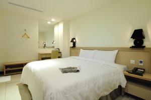 ein Schlafzimmer mit einem großen weißen Bett und einem Spiegel in der Unterkunft Bravo Hotel in Taichung