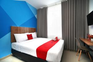 日惹的住宿－RedDoorz Plus @ Terban Residence，一间卧室配有一张红色和蓝色墙壁的床