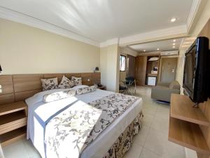 Un dormitorio con una cama grande y un televisor. en Wynn Batel, en Curitiba