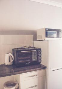 a microwave sitting on top of a counter next to a refrigerator at Collie Motel in Collie