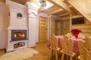a dining room with a table and a fireplace at Folk Resort Domki i Apartamenty in Murzasichle