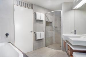 a white bathroom with two sinks and a shower at Peppers Noosa Resort and Villas in Noosa Heads