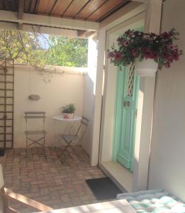 een veranda met een groene deur en een tafel met een plant bij La Casetta in Galaxidhion