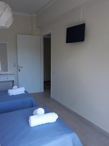 two towels on two beds in a room with a television at Rois Appartments in Poros