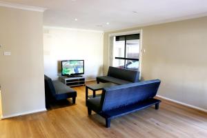 a living room with two chairs and a tv at Isle of Serenity Charming House in Keysborough