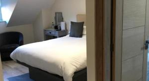 a bedroom with a white bed and a chair at Oakham Hotel in Oakham