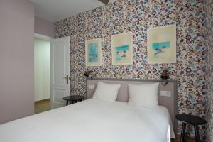 コニル・デ・ラ・フロンテーラにあるPiso Conilの花柄の壁紙を用いたベッドルーム1室(白いベッド1台付)