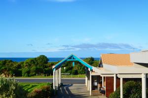 Beachfront Motel في خليج أبولو: مبنى ذو سقف أزرق مع المحيط في الخلفية