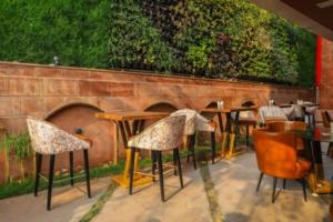 restauracja ze stołami i krzesłami obok ściany z cegły w obiekcie Hotel Golden - I w mieście Raipur