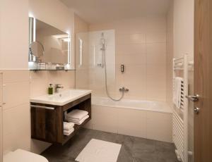 a white bathroom with a sink and a bath tub at ArlbergResort Klösterle in Klösterle