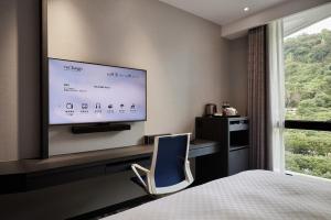 a hotel room with a bed and a tv on the wall at The Tango Hotel Taipei Shilin in Taipei