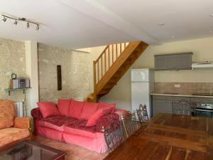 sala de estar con sofá rojo y cocina en Gite L'Eglantier, en Luçon