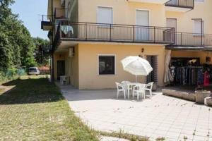 eine Terrasse mit einem Tisch und einem Sonnenschirm vor einem Haus in der Unterkunft Appartamento da Simone a Rosolina Mare in Rosolina Mare