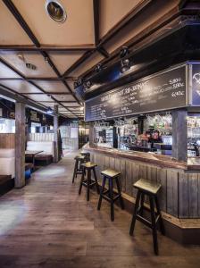 a restaurant with stools and a counter with a bar at Hotel Seurahuone Riihimäki in Riihimäki