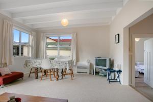 a living room with a table and chairs and a tv at Clara's Togs and Towels - Waihi - Bachcare NZ in Waihi Beach