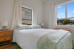 a bedroom with a white bed and a window at Clara's Togs and Towels - Waihi - Bachcare NZ in Waihi Beach