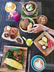 a table with plates of food and a person reaching for a plate of food at Bali Dive Resort and Spa in Tulamben