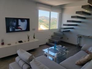 sala de estar con sofá, TV y escaleras en Loft of Love en Frigiliana