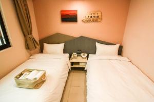 2 posti letto in una piccola stanza con un tavolo tra loro di Mayu Hotel a Nangan