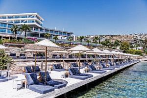 a row of chairs and umbrellas on a dock with water at Cape Bodrum Luxury Hotel & Beach in Gundogan