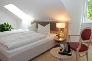 a bedroom with a white bed and a chair at Der Eichenhof in Hellwege