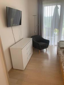 a living room with a tv and a white cabinet and a chair at Apartment am Weinberg in Ehrenhausen