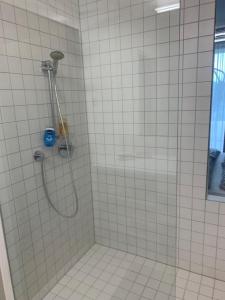 a shower with a hose in a white tiled bathroom at Apartment am Weinberg in Ehrenhausen