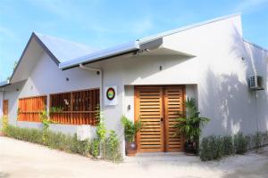 a white house with a wooden door on it at Escapism Maldives in Feridhoo