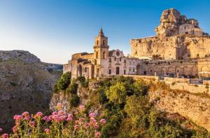 a building on the side of a mountain with flowers at Il Corbezzolo in Matera