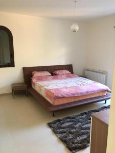 a bedroom with a bed with pink sheets and a rug at Beit Misk in Beirut