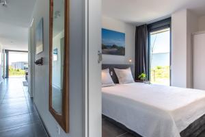 een slaapkamer met een bed en een groot raam bij De Groote Duynen in Kamperland