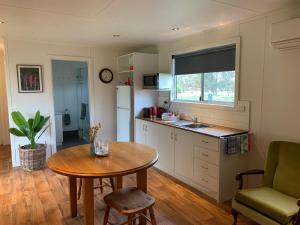 a kitchen with a table and a sink and a table at Mascot Cottage - Pet Friendly and Complimentary Breakfast Hamper in West Wyalong