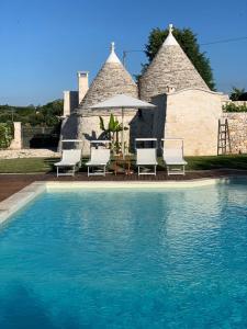 una piscina con sedie, tavolo e ombrellone di Borgo D'Itria a Monopoli
