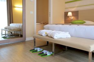 a bedroom with a bed with towels on a bench at Enjoy Garda Hotel in Peschiera del Garda