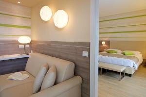 a room with two beds and a couch in a room at Enjoy Garda Hotel in Peschiera del Garda