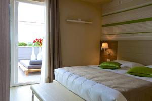 a bedroom with a bed with green pillows and a balcony at Enjoy Garda Hotel in Peschiera del Garda