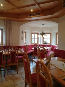 a dining room with a red couch and tables at Zur Guten Einkehr in Bayrischzell