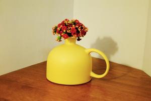 un vaso giallo con dei fiori sul tavolo di B&B A Casa di Tiziana - Roma a Roma