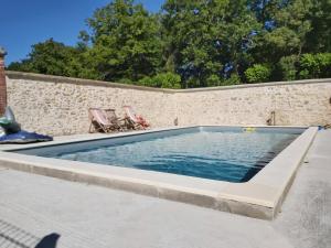 uma piscina com duas cadeiras e uma parede em Château de la Malmaison em Champillon