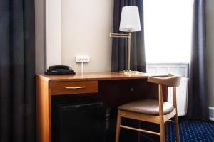 a desk with a lamp and a chair in a room at City Hotel Nebo in Copenhagen