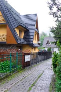 a house with a black roof and a fence at Pokoje Gościnne Centrum Nowotarska in Zakopane