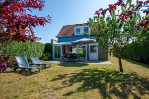 Una casa con dos sillas y una sombrilla en el patio. en Antibes 236 - Kustpark Village Scaldia, en Hoofdplaat