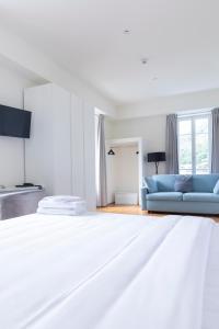 a white bedroom with a blue couch and a bed at Lac Hotel in Melide