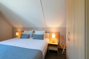 Un dormitorio con una cama con dos almohadas azules. en Antibes 236 - Kustpark Village Scaldia, en Hoofdplaat