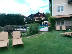 a yard with chairs and a pool and a house at Alpen Hotel Eghel in Folgaria